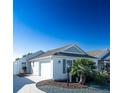 House exterior featuring a two-car garage and a palm tree at 1750 Kingfisher Ct, The Villages, FL 32162