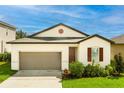 Inviting single-story home featuring an attached garage, complemented by lush greenery and vibrant landscaping, offering a cozy and attractive facade at 555 Meadow Pointe Dr, Haines City, FL 33844