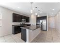 Modern kitchen with dark cabinetry, granite countertops, and stainless steel appliances at 555 Meadow Pointe Dr, Haines City, FL 33844