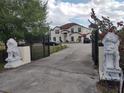 View of the property from the gate featuring lion statues, a large driveway, mature trees, and the home at 18744 Sabal St, Orlando, FL 32833