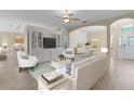 Bright, open living room featuring neutral tones, ceiling fan, and archway to the dining area at 25304 Forest Oak Ct, Leesburg, FL 34748