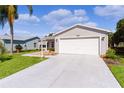 Inviting home featuring a well-kept lawn, spacious driveway, and an attached two-car garage at 803 Camino Del Rey Dr, The Villages, FL 32159
