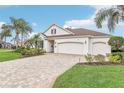 Charming single-story home with a paver driveway, three-car garage, well-kept lawn, and lush tropical landscaping at 1596 Birmingham Ter, The Villages, FL 32162