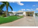 Charming single-story home featuring a well-maintained lawn, mature palm tree, and convenient covered carport at 1704 Pebble Beach Ln, Lady Lake, FL 32159