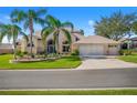 Tan two-story house with palm trees and a three-car garage at 5740 Bounty Cir, Tavares, FL 32778
