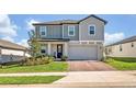 Attractive two story home with a brick driveway, front lawn, and neutral grey trim and siding at 2298 Raven Ridge Rd, Minneola, FL 34715