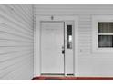 A white front door with a window panel and visible smart lock features on a light colored house at 956 Chula Ct, The Villages, FL 32159