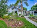 Quaint two-story home with a lush, landscaped front yard with palm trees and white siding at 351 W 10Th Ave, Mount Dora, FL 32757