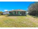 House exterior showcasing a screened porch and large backyard at 26701 Bimini Dr, Tavares, FL 32778