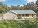 Charming single-story home featuring a light beige exterior, metal roof, and well-manicured lawn at 3200 Se 20Th Ln, Sumterville, FL 33585