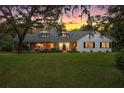 Charming one-story home with manicured lawn and mature trees at sunset at 9345 Silver Lake Dr, Leesburg, FL 34788