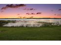 Scenic lake view at sunset featuring colorful sky, calm water, and lush green grass at 9345 Silver Lake Dr, Leesburg, FL 34788