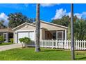 Inviting single-story home with an attached garage, screened porch, and a well-maintained lawn with a palm tree at 17478 Se 77Th Sycamore Ave, The Villages, FL 32162
