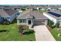 Aerial view of home with front lawn, landscaped garden, neutral paint, two car garage, and concrete driveway at 1089 Fig St, Tavares, FL 32778