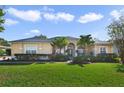 Single-story home with tan exterior, lush landscaping, and palm trees at 23436 Valderama Ln, Sorrento, FL 32776