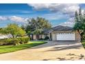 Well-kept home boasting a spacious driveway, an attached two-car garage, and manicured green lawn at 33516 Overton Dr, Leesburg, FL 34788