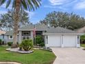 Charming home featuring a two-car garage, manicured lawn, and mature landscaping with palm tree at 20744 Queen Alexandra Dr, Leesburg, FL 34748