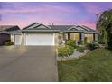 Two-story house exterior with a two car garage, landscaping, and warm lighting at 1315 Greenville Way, The Villages, FL 32162