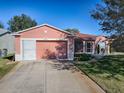 Single-story home with a well-maintained lawn and attached two-car garage at 33236 Grand Cypress Way, Leesburg, FL 34748