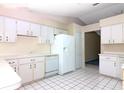 Bright kitchen features white cabinets, a dishwasher, and a refrigerator, with tile flooring at 21502 King Henry Ave, Leesburg, FL 34748