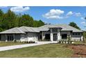 Elegant single-story home with a gray roof, stone accents, and a well-manicured lawn on a sunny day at 16914 Vinci Way, Bella Collina, FL 34756