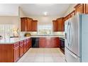Charming kitchen with wood cabinets, black appliances, and a stainless steel refrigerator at 973 Belle Oak Dr, Leesburg, FL 34748
