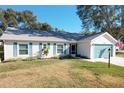 Charming single-story home featuring a well-maintained lawn, light siding, teal shutters, and a matching garage door at 4800 Tara View Rd, Leesburg, FL 34748