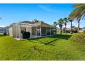 A spacious backyard with a screened-in lanai, pergola, and lush green grass at 1313 La Estrellita Way, The Villages, FL 32162