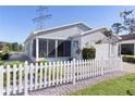 Gray house with white picket fence, attached garage, and screened porch at 1639 Campos Dr, The Villages, FL 32162