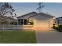 Gray house with white picket fence and attached garage at dusk at 1639 Campos Dr, The Villages, FL 32162
