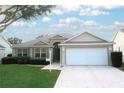 Tan house with a white garage door and well-manicured lawn at 1897 Caryle Ln, The Villages, FL 32162