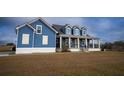 Inviting blue two-story home featuring a charming front porch and well-manicured lawn at 2437 Bay Lake Loop, Groveland, FL 34736