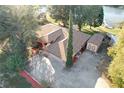 Aerial view of house with large driveway, shed, and mature landscaping situated near a lake at 9835 Lakeshore Dr, Clermont, FL 34711
