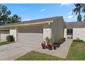 Charming villa featuring a two-car garage and lovely curb appeal with colorful potted plants and well-kept landscaping at 2247 Cypress Cove Dr # E2, Tavares, FL 32778