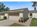Charming villa featuring a two-car garage and lovely curb appeal with colorful potted plants and well-kept landscaping at 2247 Cypress Cove Dr # E2, Tavares, FL 32778