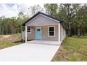 Inviting single-story house with new concrete driveway and light blue door, surrounded by lush greenery at Lot 17 Indian Estates Cr 423, Lake Panasoffkee, FL 33538