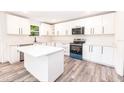 Modern kitchen featuring white cabinets, an island, stainless appliances, and stylish wood-look flooring at Lot 17 Indian Estates Cr 423, Lake Panasoffkee, FL 33538