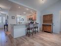 Open dining area featuring wood floors, a breakfast bar with seating, and a charming china cabinet at 17242 Se 94Th Coults Cir, The Villages, FL 32162