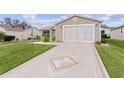 Tan house with a decorative driveway and landscaping at 17466 Se 75Th Coachman Ct, The Villages, FL 32162