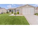 Tan house with a garage and well-manicured lawn at 17466 Se 75Th Coachman Ct, The Villages, FL 32162