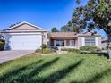 Tan house with a two-car garage and manicured lawn at 16914 Se 96Th Chapelwood Cir, The Villages, FL 32162