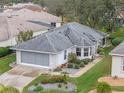 White ranch home with grey roof, screened garage, and landscaped yard at 5520 Sir Churchill Dr, Leesburg, FL 34748