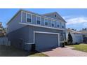 Two-story house with gray siding, a brick driveway, and landscaping at 1710 Summer Rose Dr, Mount Dora, FL 32757
