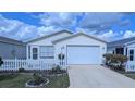 Inviting single-story home featuring a well-manicured lawn, white picket fence, and an attached garage at 3449 Roanoke St, The Villages, FL 32162
