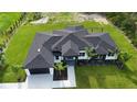 Aerial view of a modern home with a dark roof, lush green lawn, landscaping and white accents at 42157 Tamarac St, Eustis, FL 32736