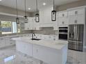 Bright kitchen with marble floors, white cabinets, island, and stainless steel appliances at 42200 Chinaberry St, Eustis, FL 32736