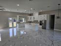 Bright kitchen with marble floors, white cabinets, island, and stainless steel appliances at 42200 Chinaberry St, Eustis, FL 32736