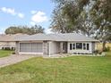 Single-story house with stone accents, screened garage, and well-manicured lawn at 5004 Saint Andrews Arc, Leesburg, FL 34748