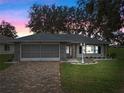 House exterior at dusk showcasing stone accents, screened garage, and landscaping at 5004 Saint Andrews Arc, Leesburg, FL 34748