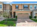 Front view of townhome featuring a two-car garage and brick driveway at 765 Walkers Grove Ln, Winter Garden, FL 34787